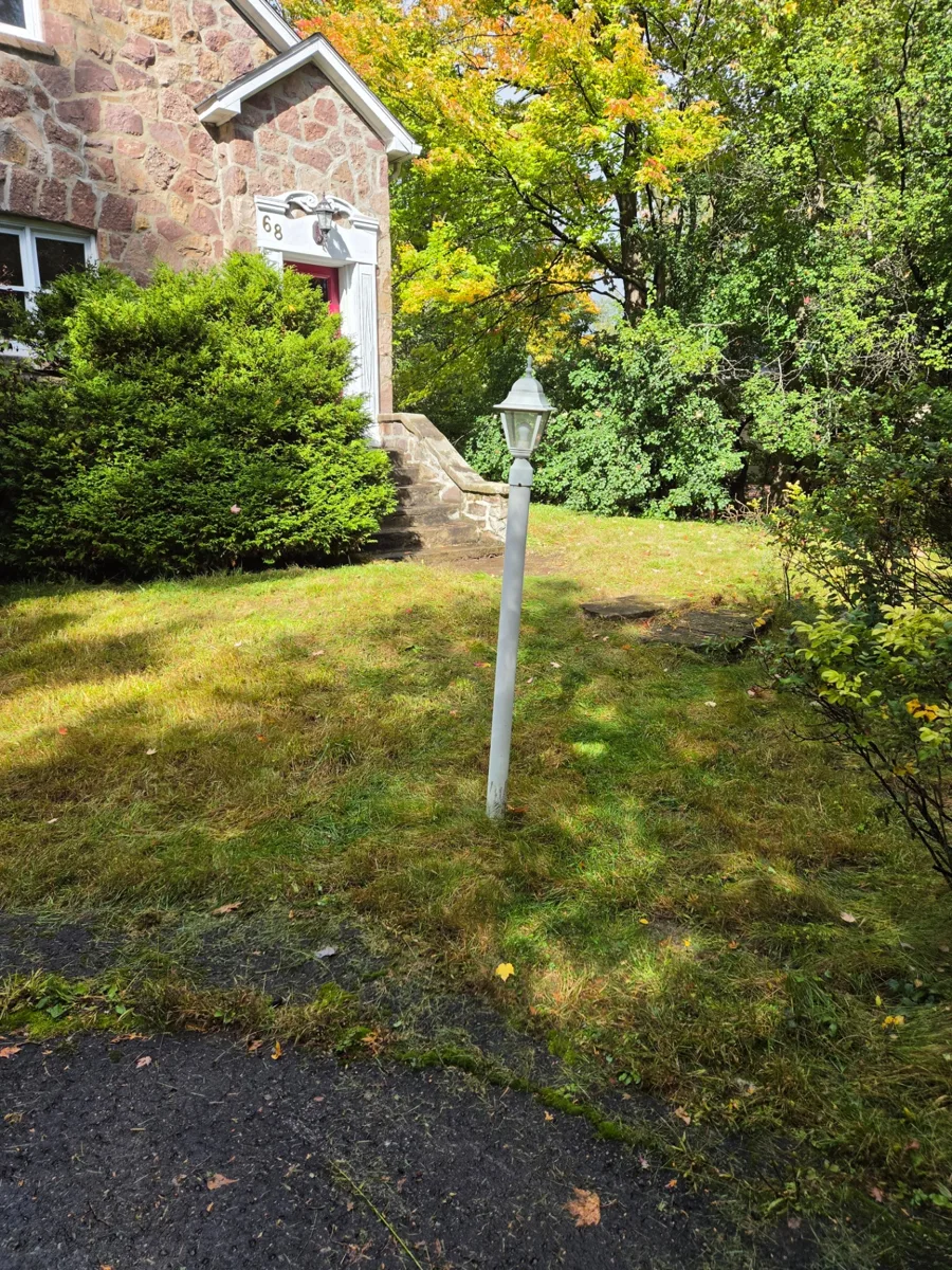 Cour avant près de l’escalier en pierre, avec l’ancien sentier en pierre presque entièrement recouvert de gazon à Hudson, au Québec.