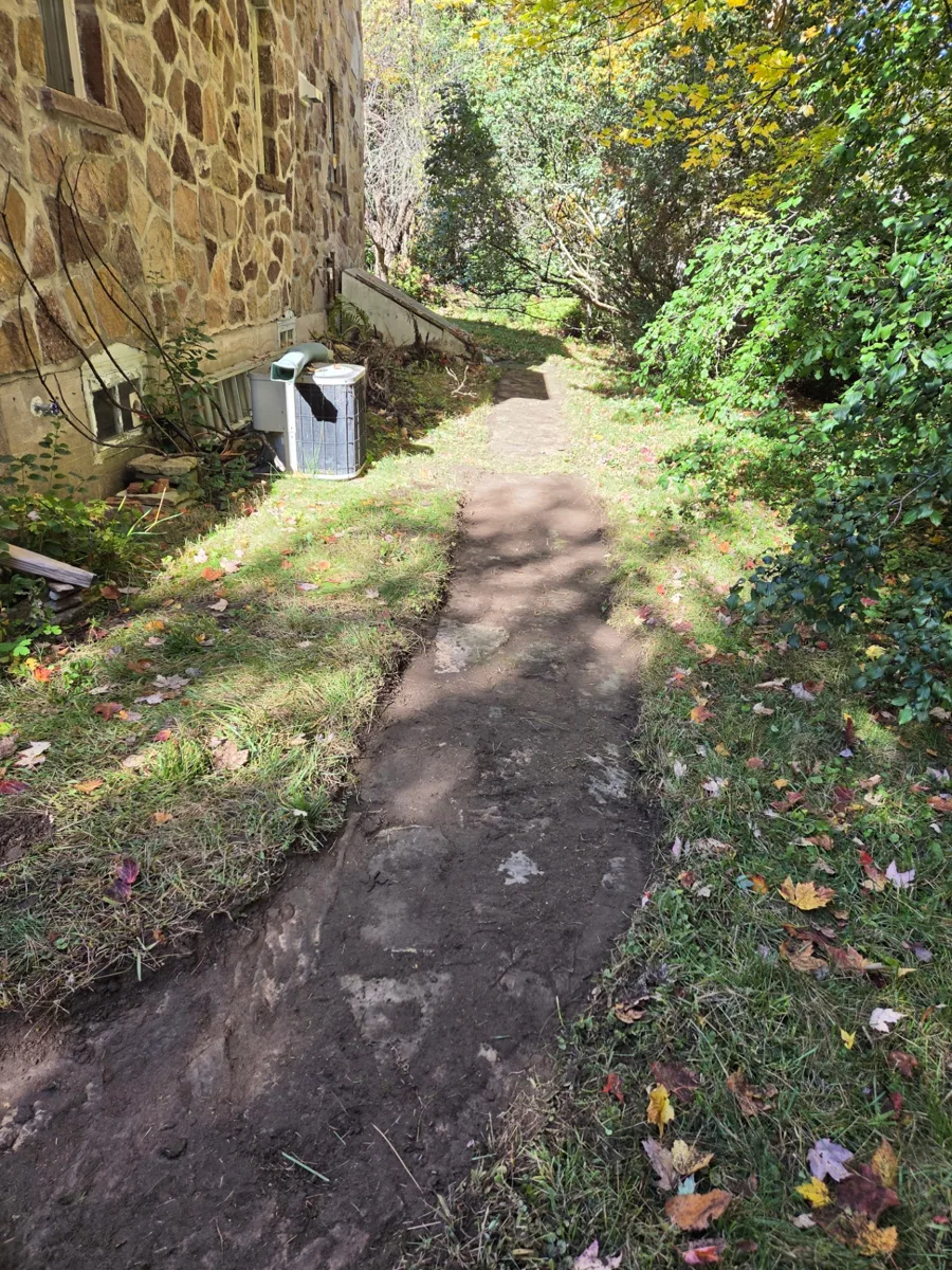 Le même passage latéral après le dégagement de la végétation, laissant voir l’ancien sentier en pierre le long de la maison à Hudson.