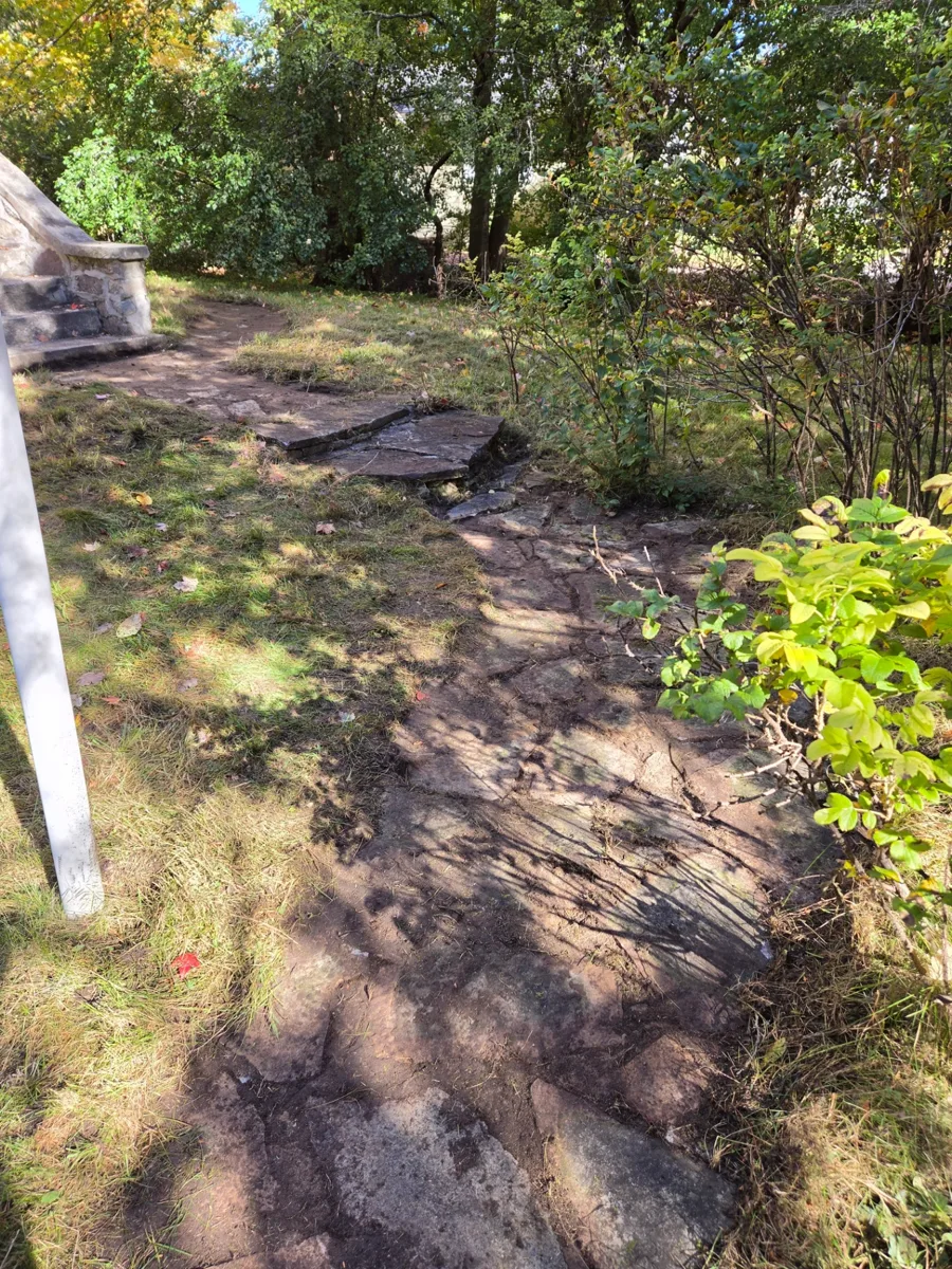 Sentier en pierre de la cour avant dégagé après l’enlèvement du gazon et de la végétation, menant à l’escalier en pierre à Hudson.