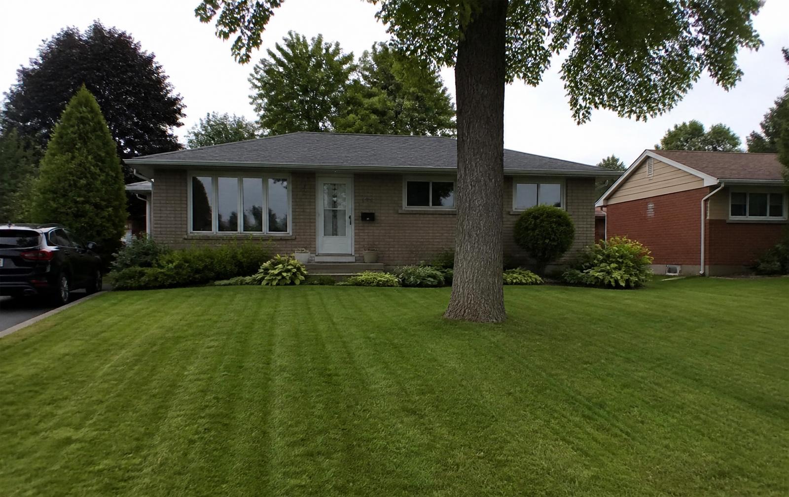 Freshly mowed and striped residential front lawn at a West Island Montreal home at golden hour